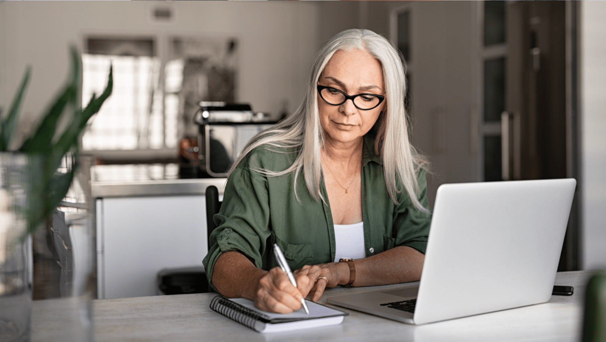 middle aged woman writing in kitchen